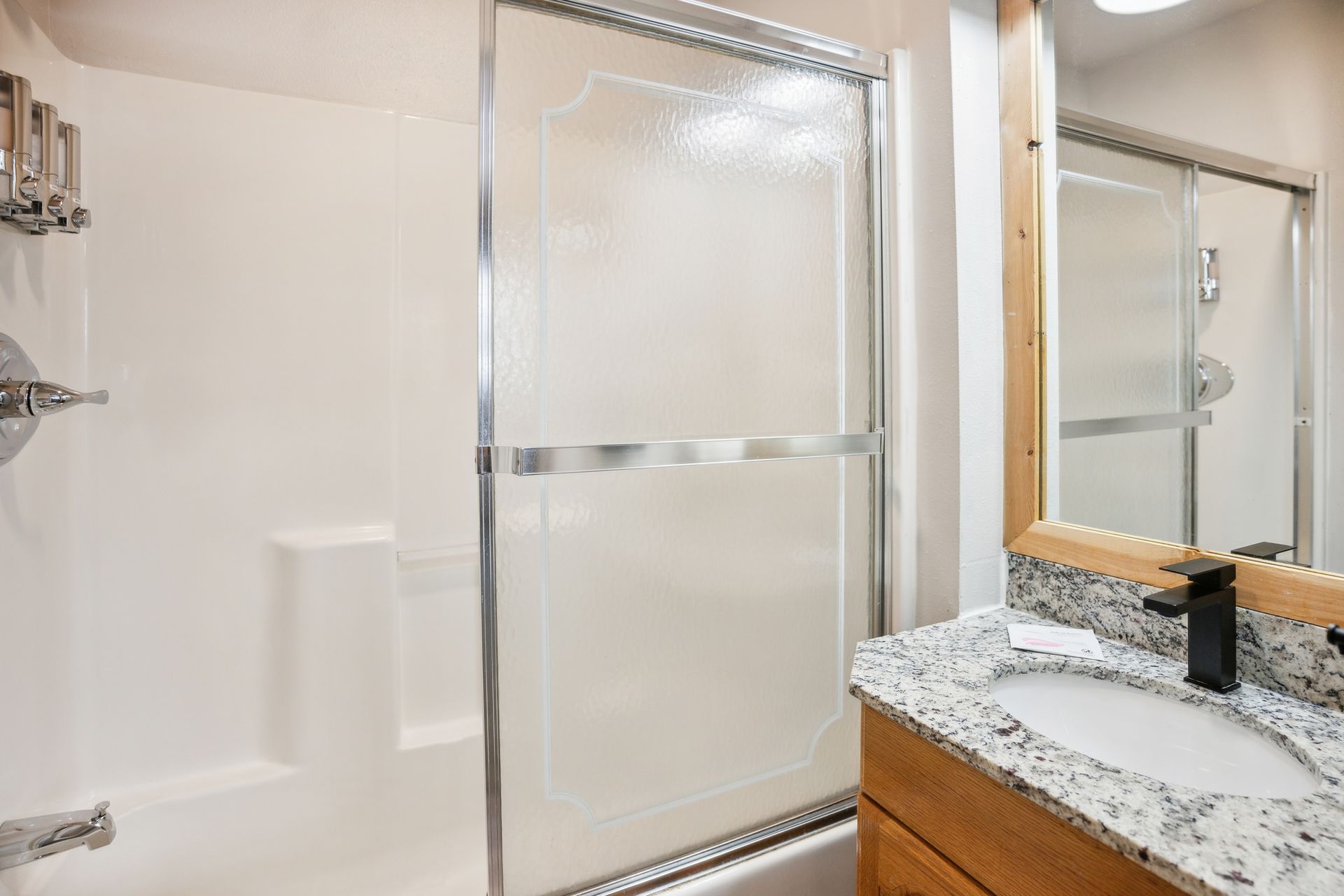 A bathroom with a sink , tub , shower and mirror.