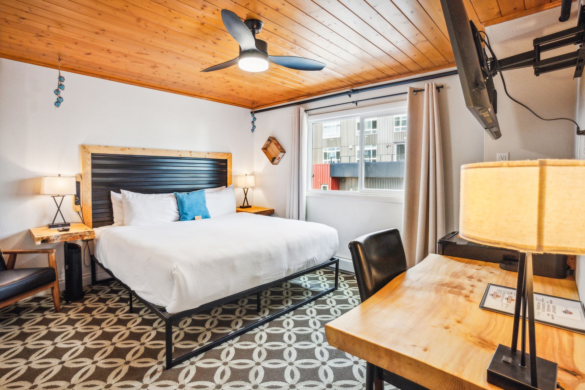 A hotel room with a king size bed , desk and television.