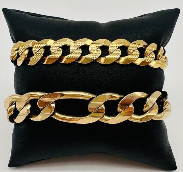 Two gold bracelets are on a black pillow