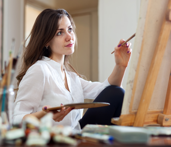 Women with brown hair painting on canvas