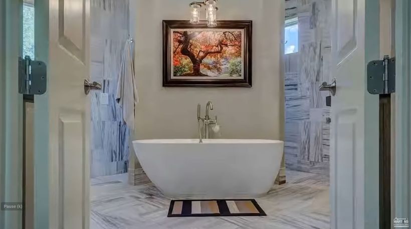 Blue Wall Bathroom with Deep White Tub and Marble Countertops. 