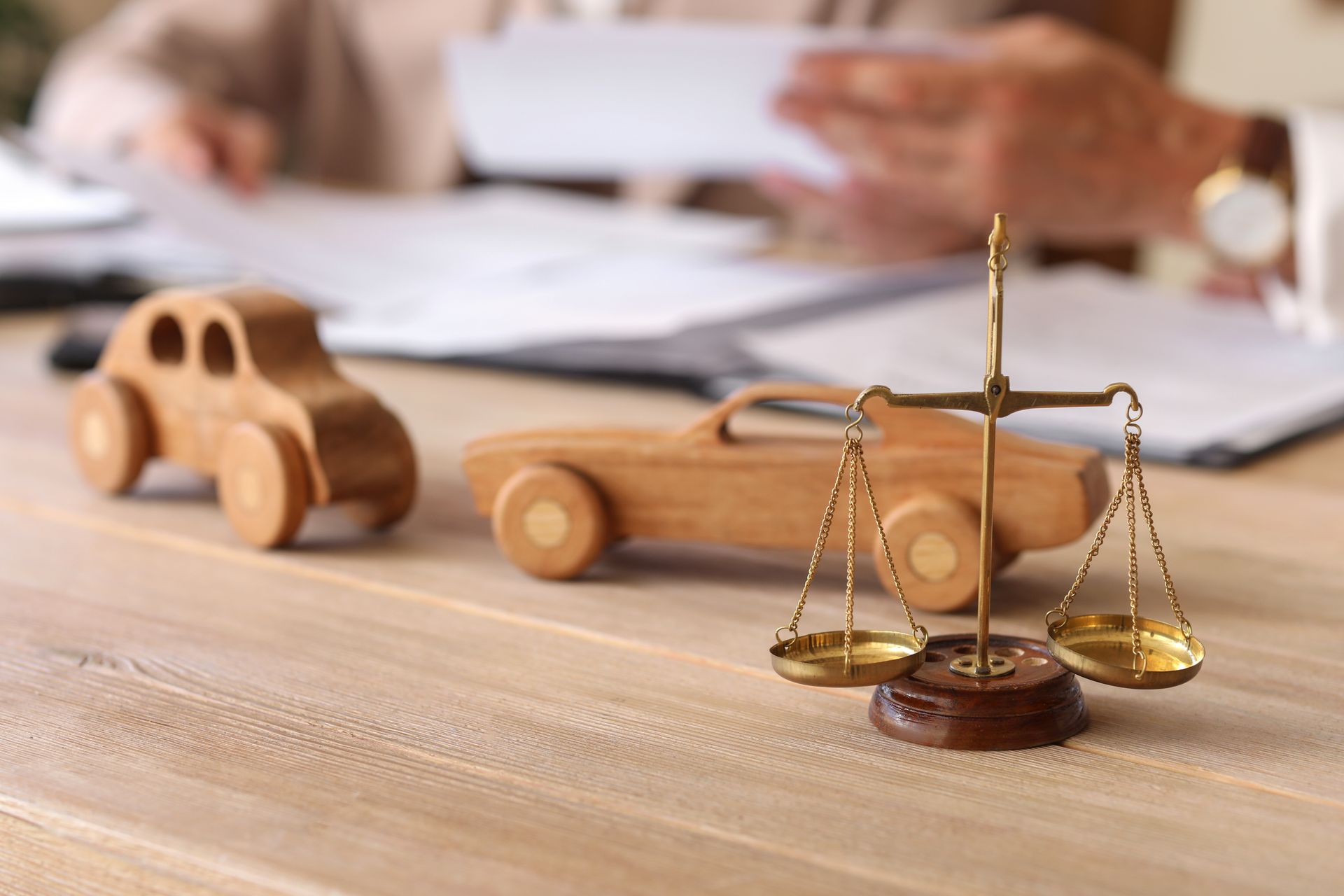 Scales of justice and wooden car models on a lawyer’s desk during an auto accident case.