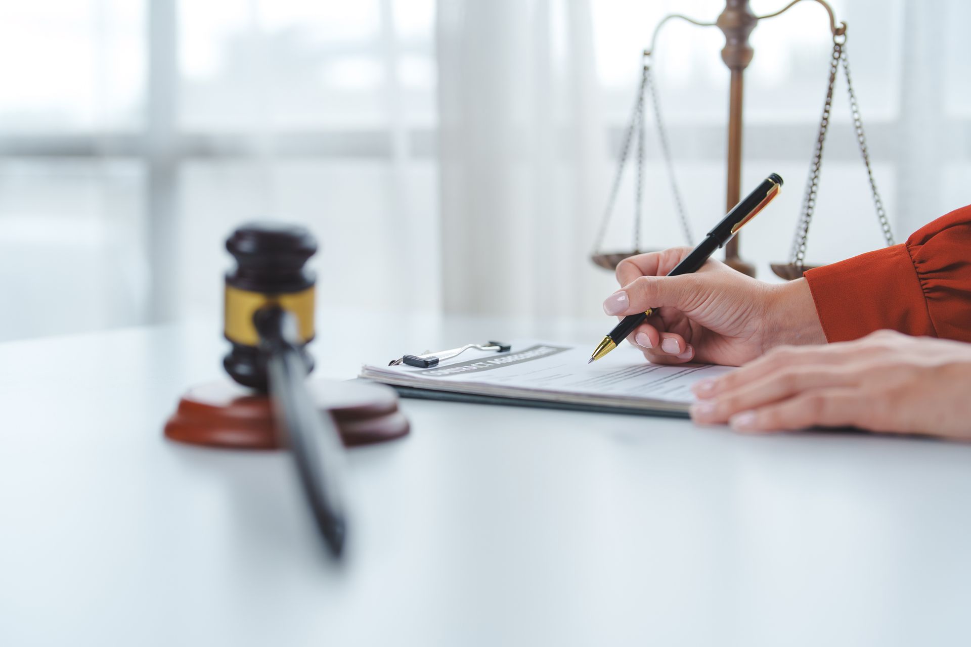 Female lawyer reviewing legal documents with gavel and scales of justice nearby. Female lawyer reviewing legal documents with gavel and scales of justice nearby.