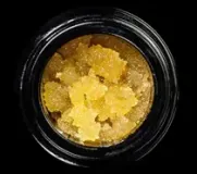Close-up of yellow crystalline concentrate in a black glass jar