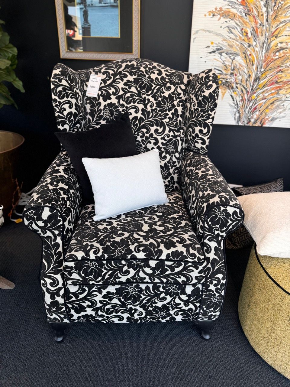 Wingback armchair with black and white floral pattern. Black and white pillows rest on the seat.