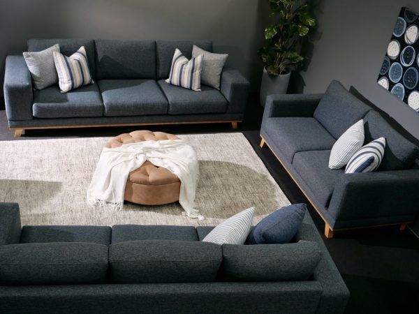 Living room furniture set in gray, including sofas, a sectional, and a round ottoman with a white throw blanket.