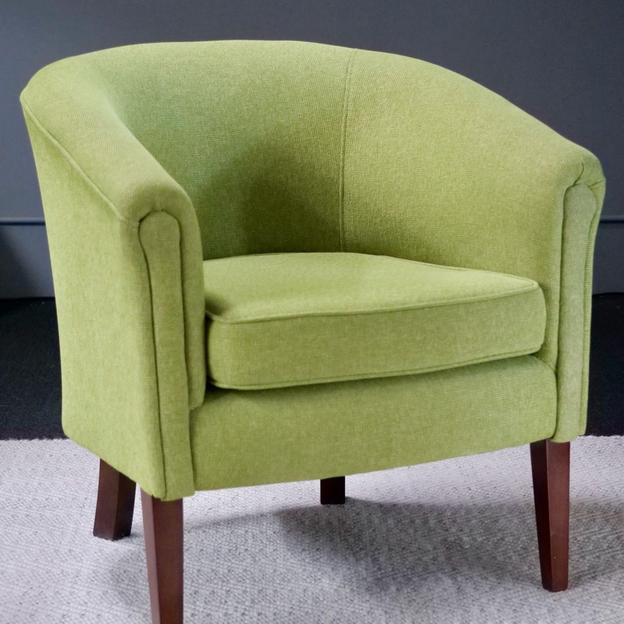 Green upholstered armchair with wooden legs.