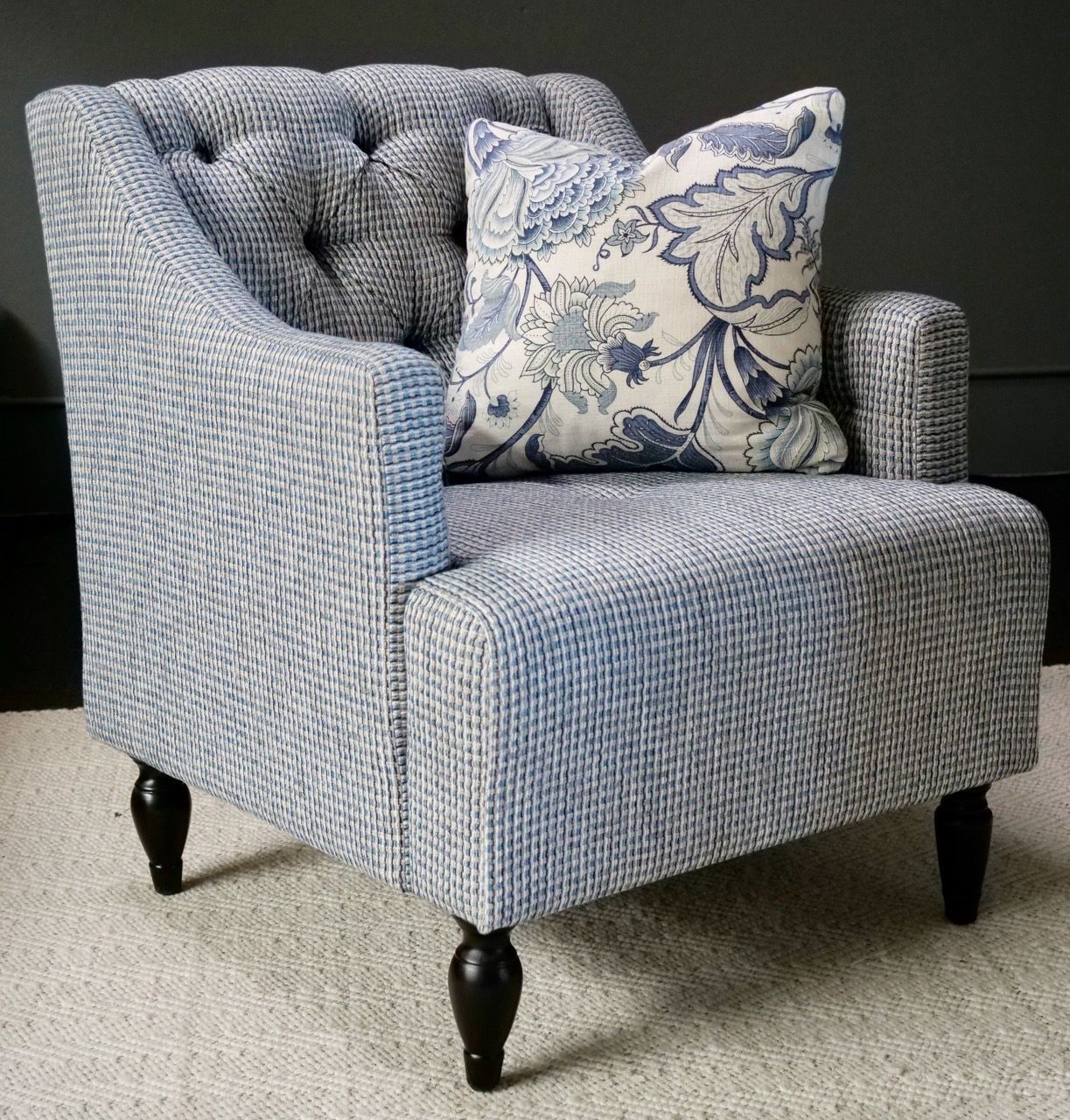 Blue upholstered armchair with a floral pillow.