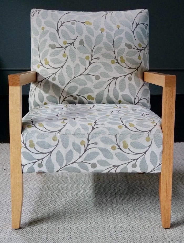 Armchair with light wood frame and botanical print upholstery.