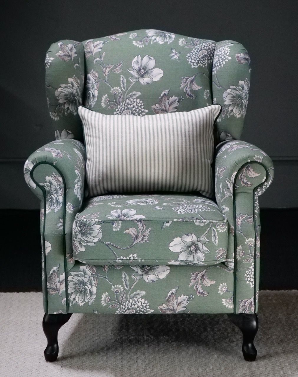 Green floral-patterned armchair with a striped pillow.