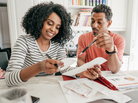 A man and a woman are sitting at a table looking at papers.