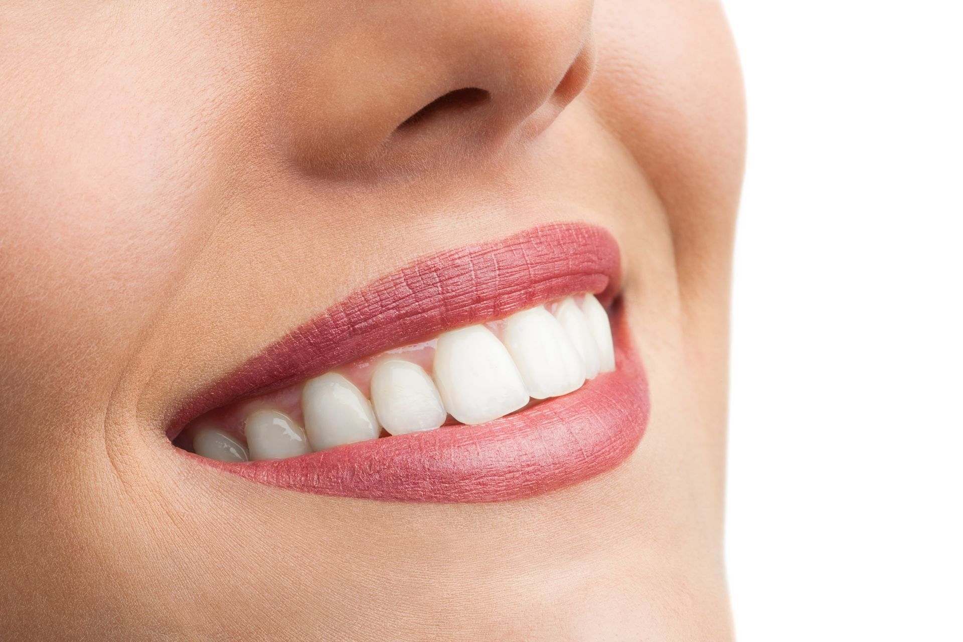 A closeup photo of a woman smiling with beautiful teeth.