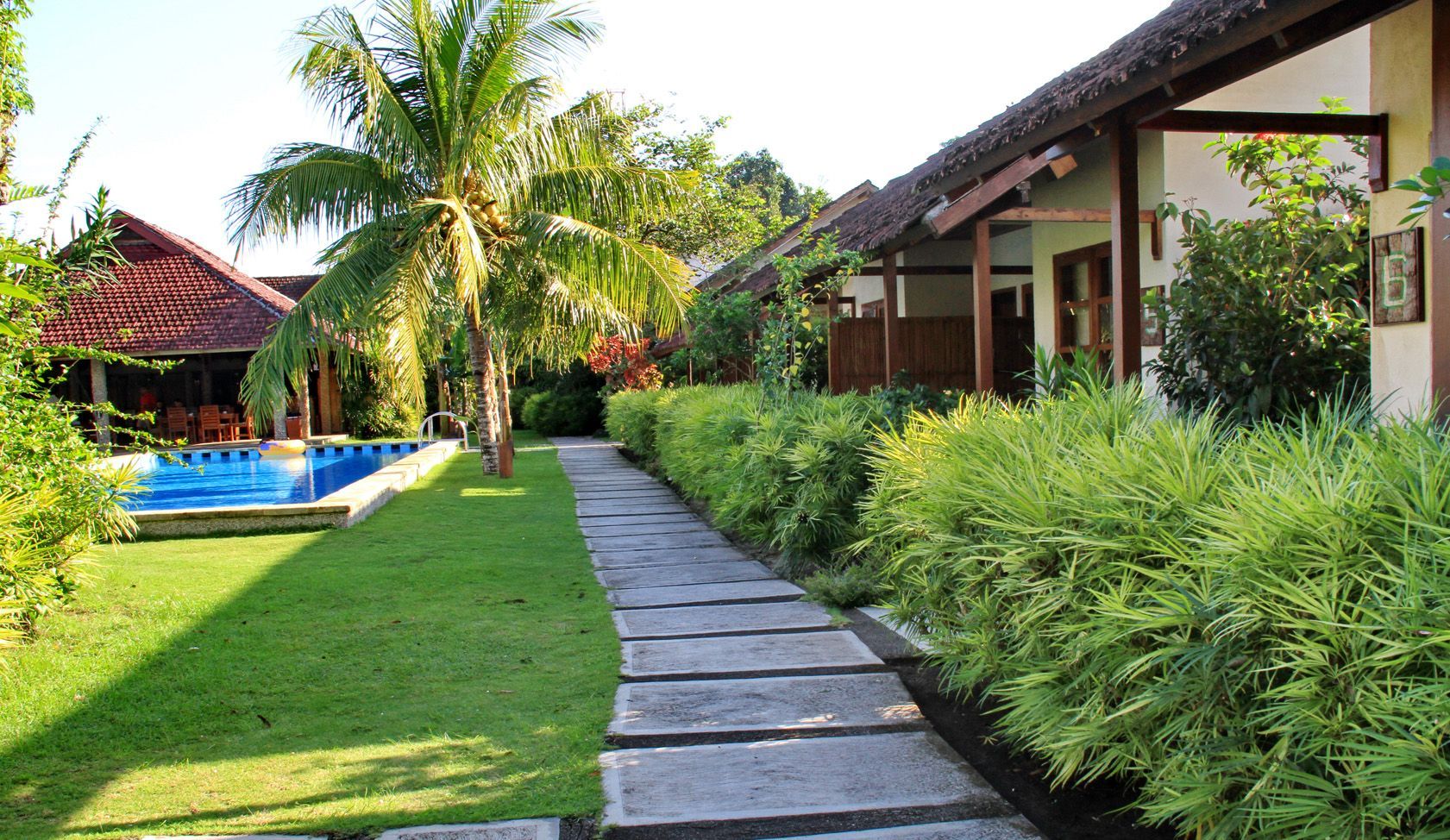 A path leading to a house with a pool in the background