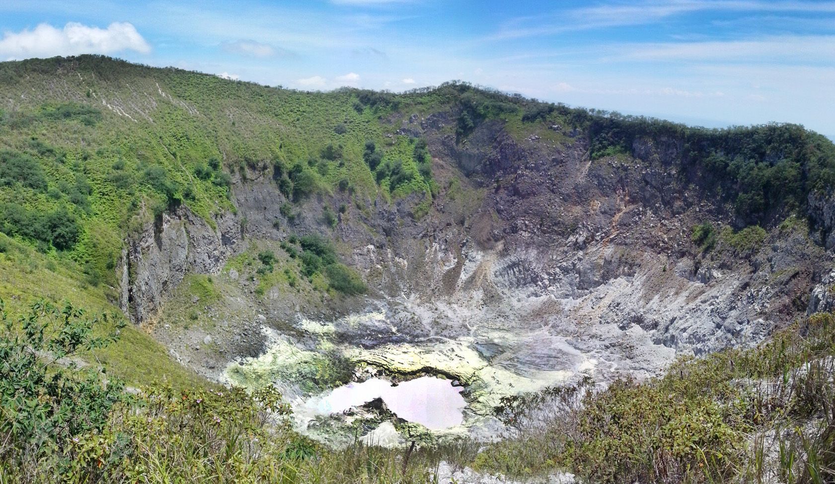 A large crater in the middle of a mountain surrounded by trees.