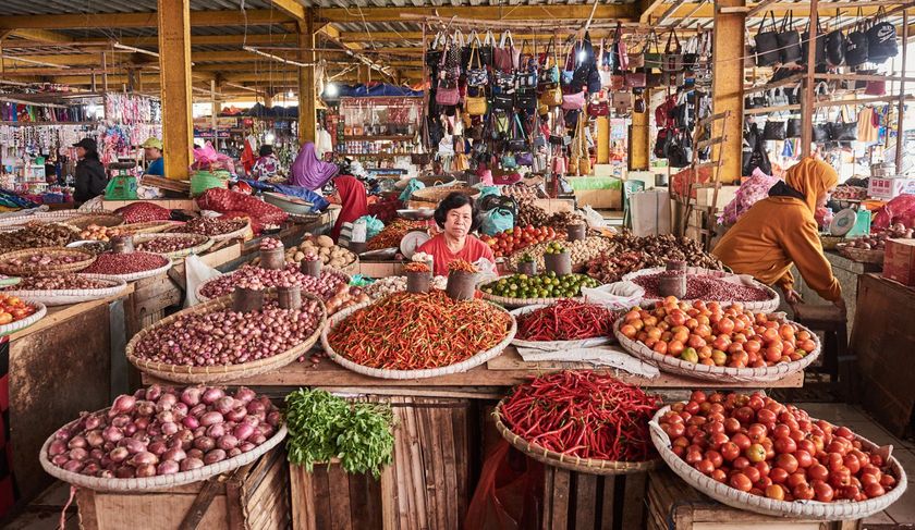 A woman is selling vegetables at a market.