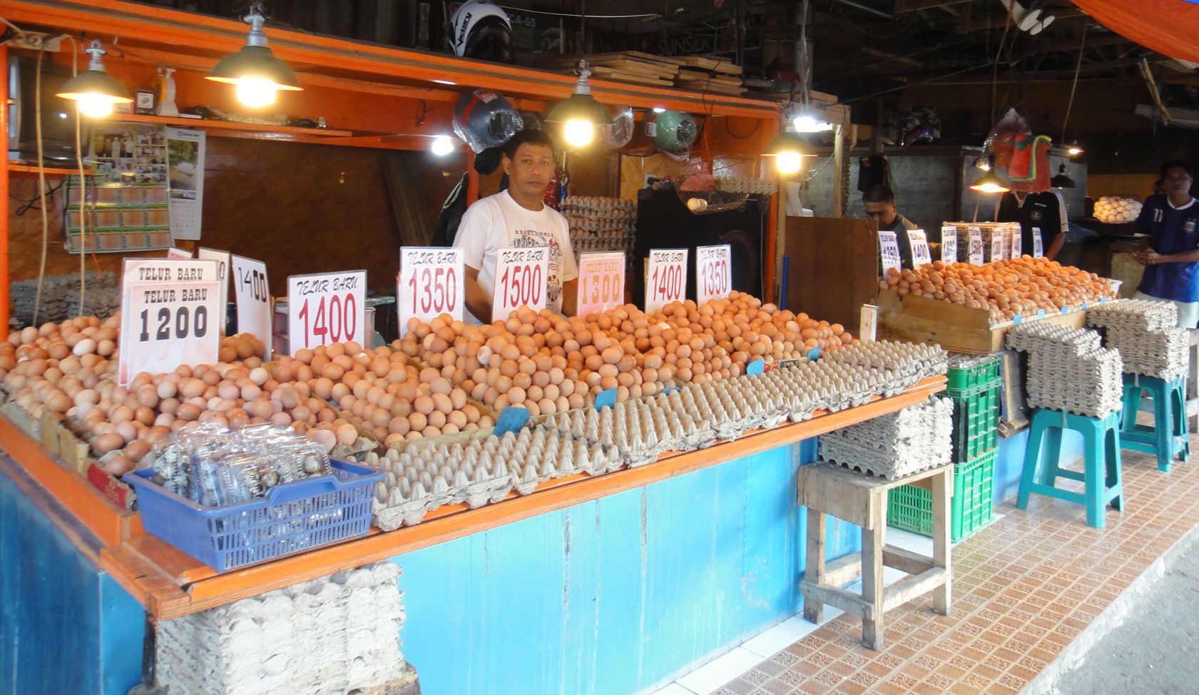 A man is standing in front of a display of eggs for sale.
