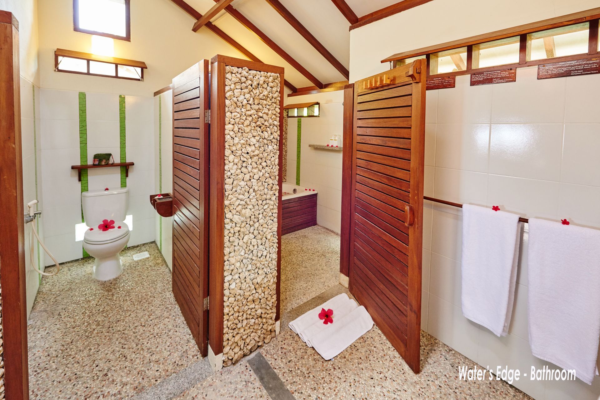 A bathroom with a toilet , shower and towels
