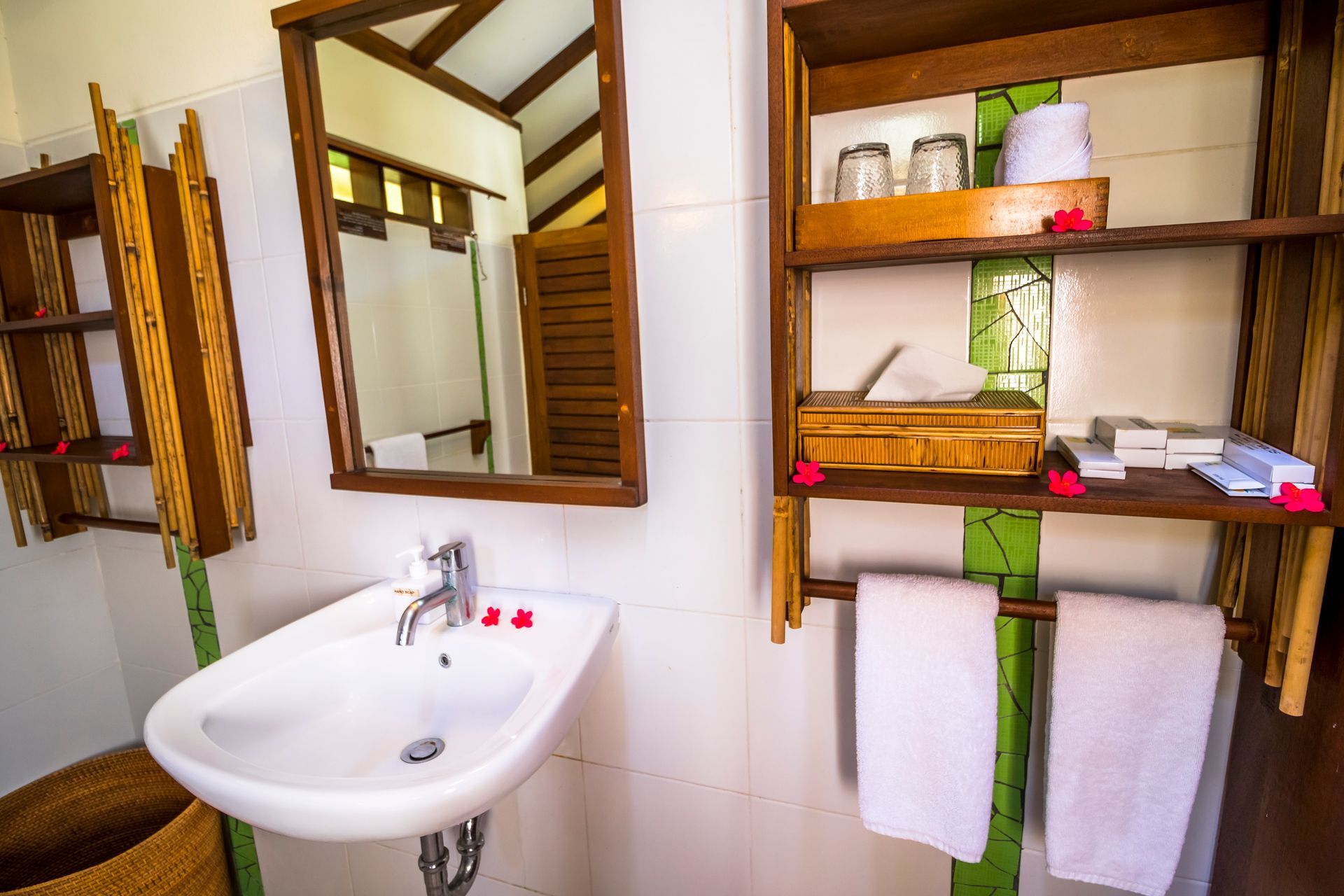 A bathroom with a sink , mirror , shelves and towels.