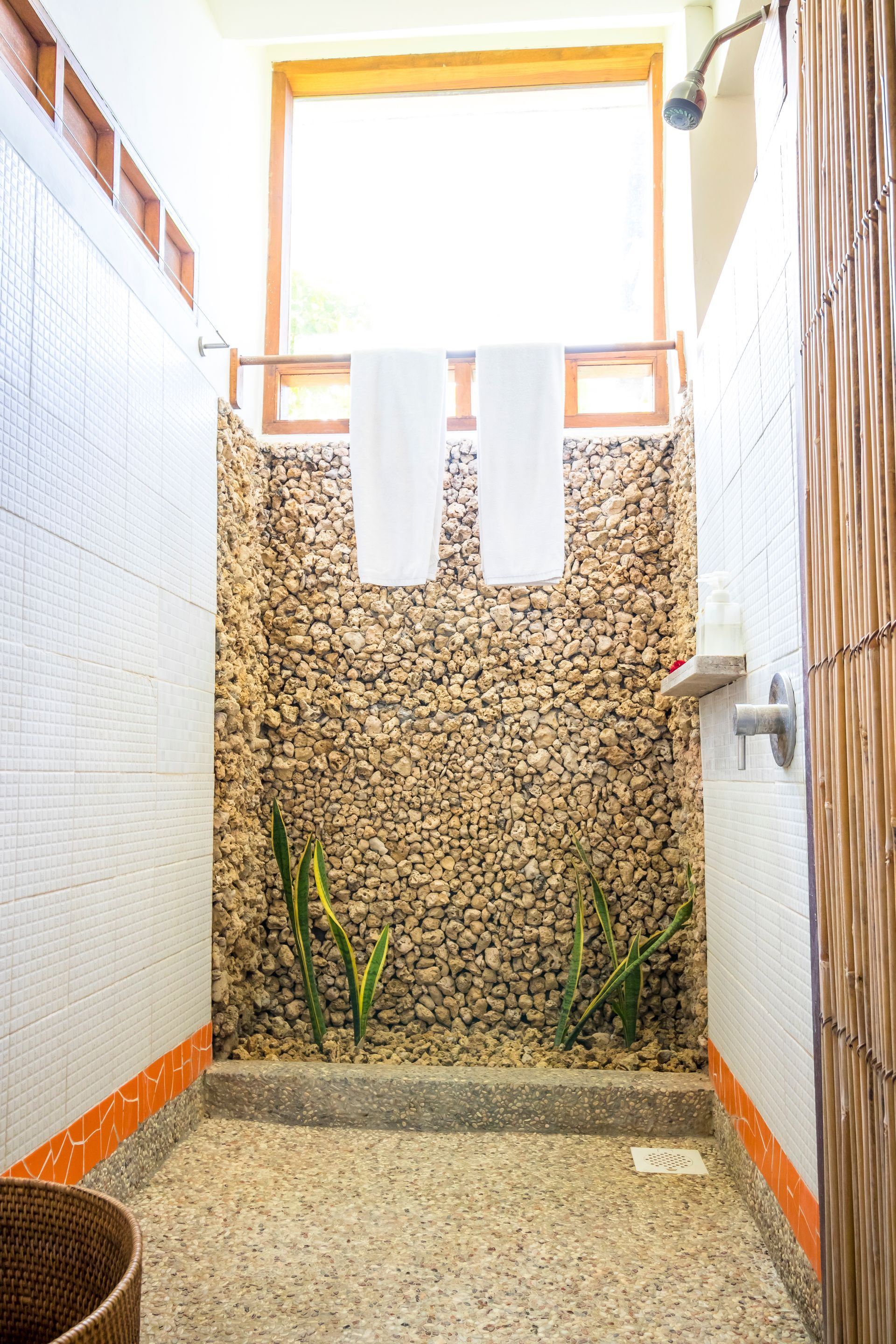 A bathroom with a walk in shower and a window.