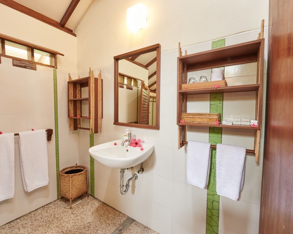 A bathroom with a sink , mirror , shelves and towels.