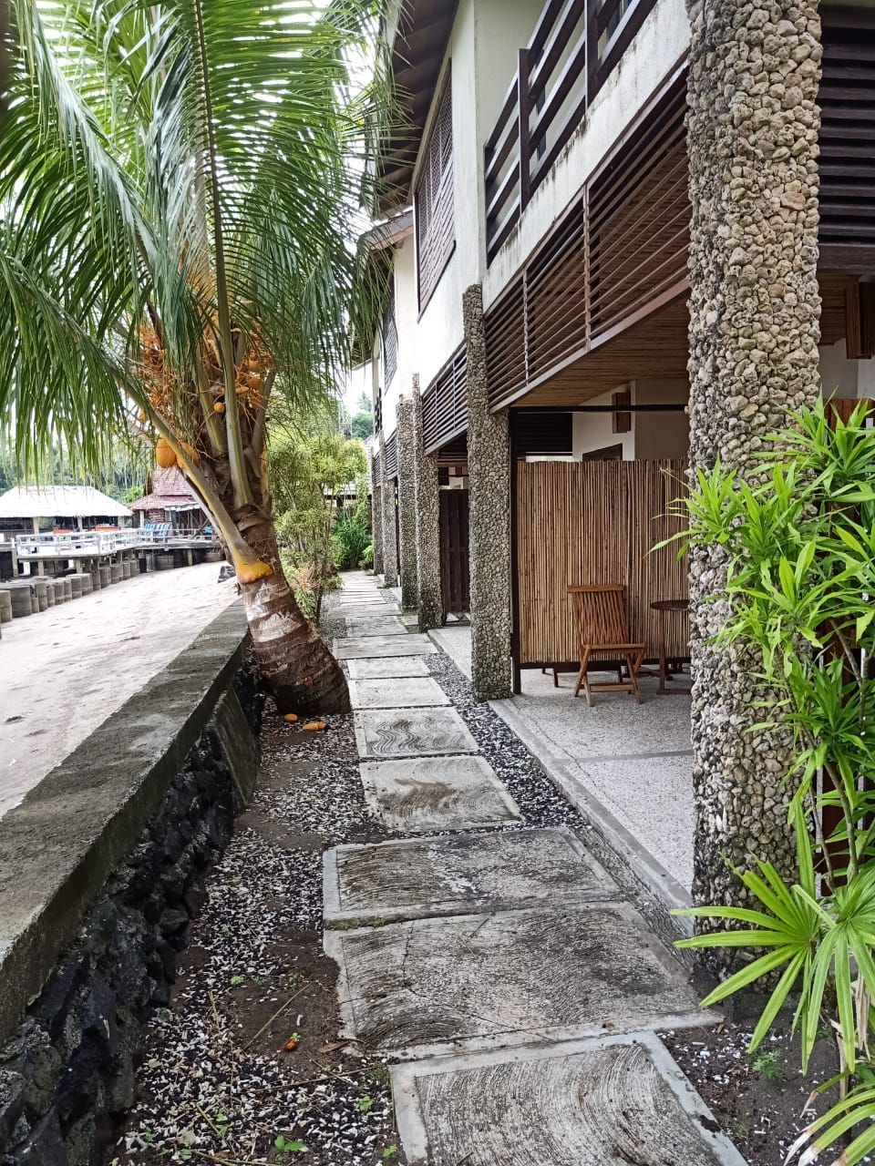 A stone walkway leading to a building with a palm tree in the background.