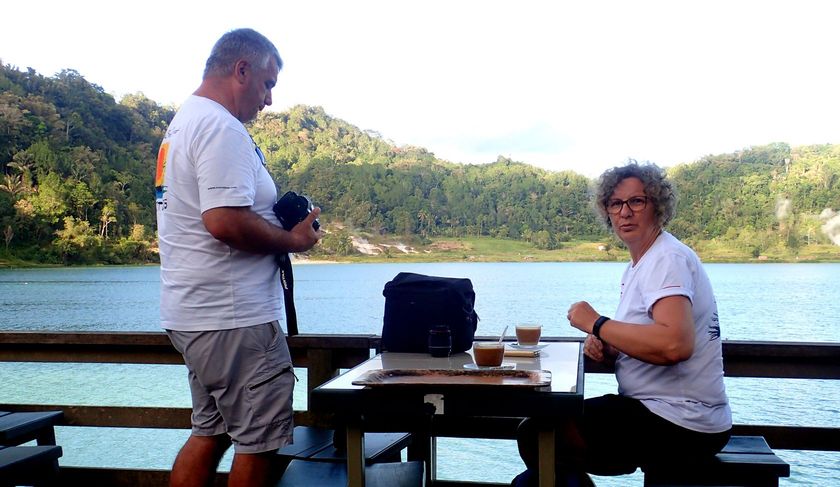 A man and a woman are sitting at a table by a lake.