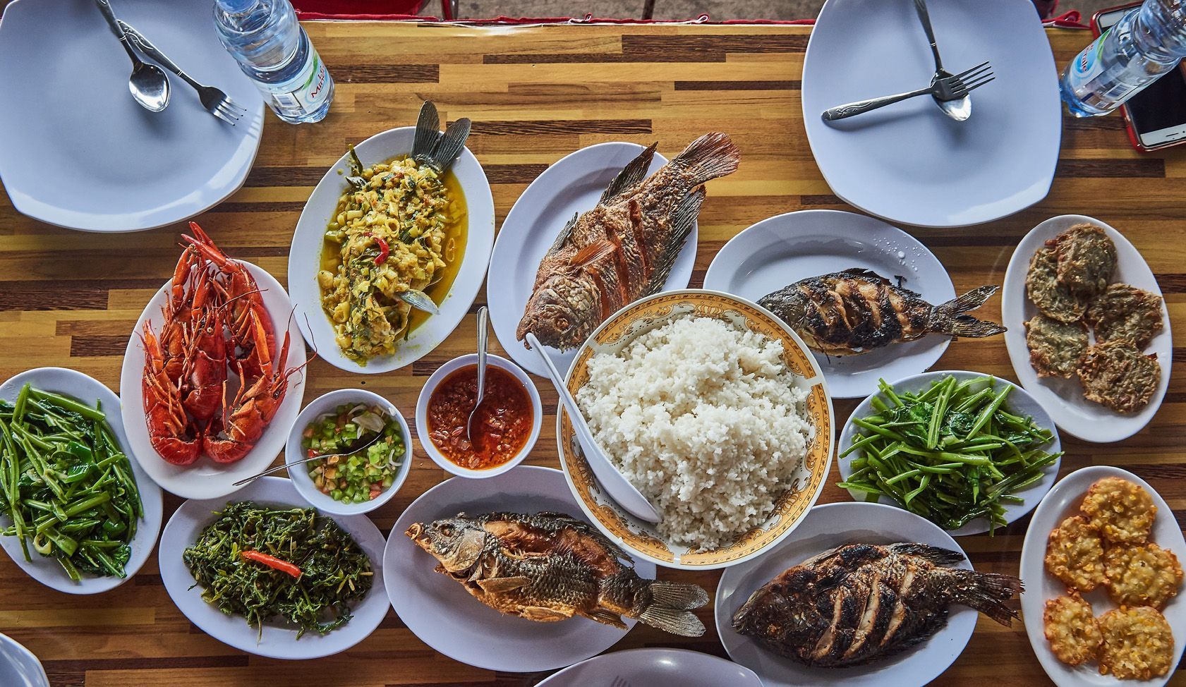 A wooden table topped with plates of food and utensils.