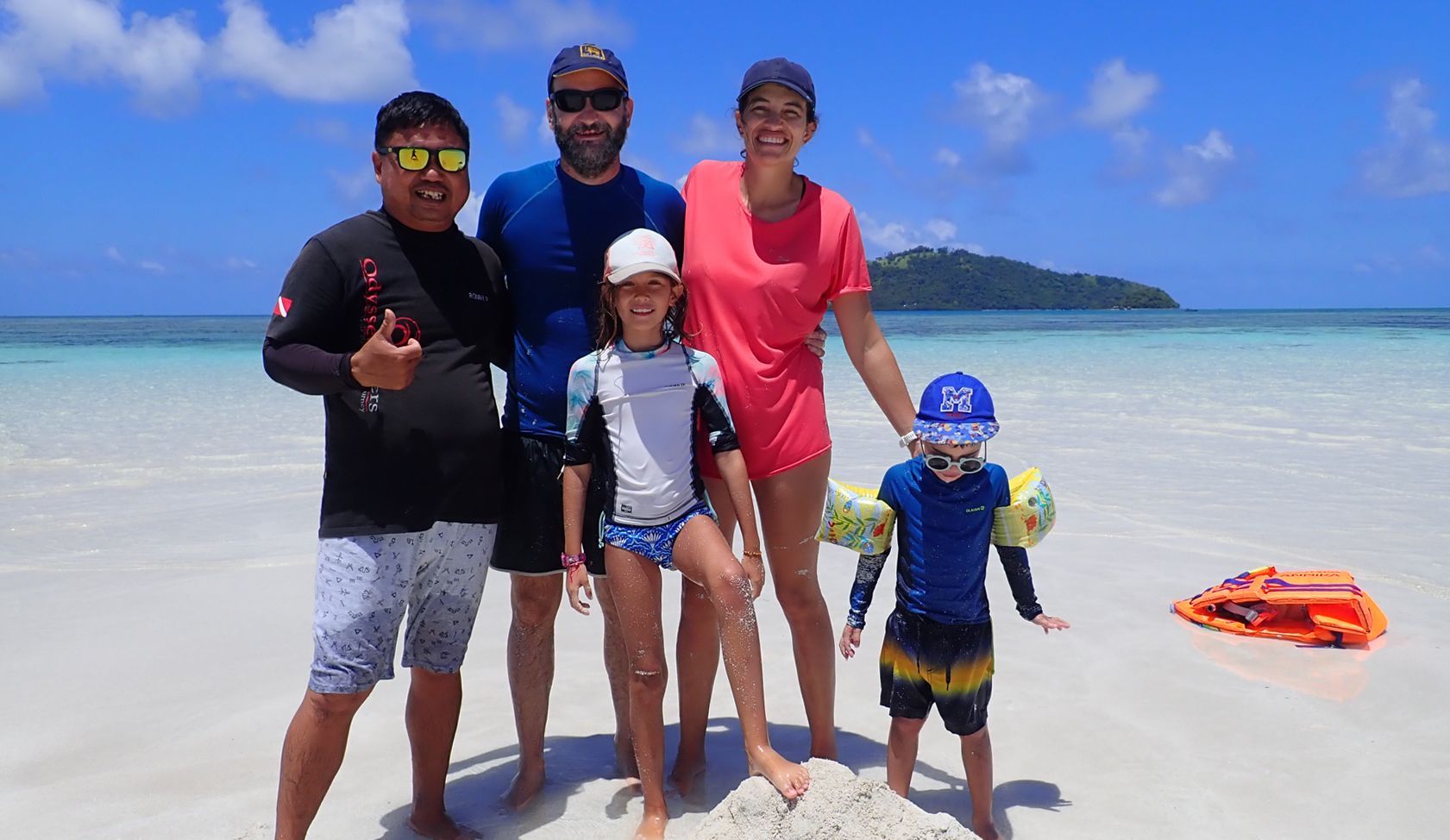 A group of people are posing for a picture on a beach.