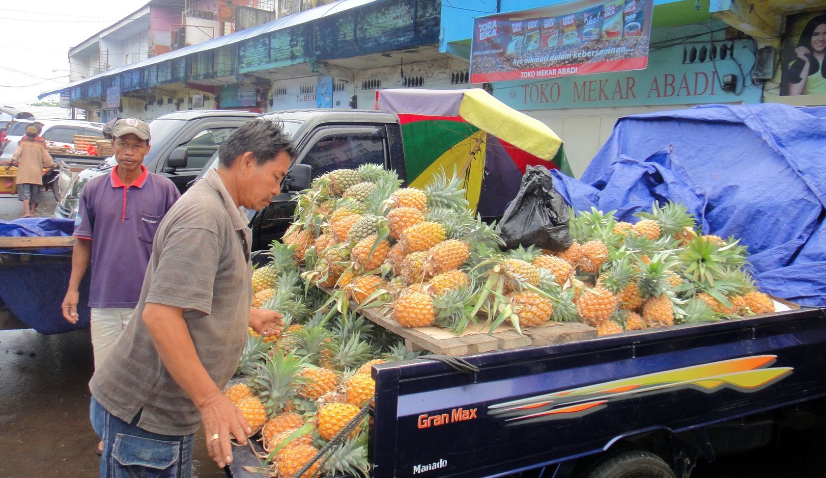 A man standing next to a truck full of pineapples