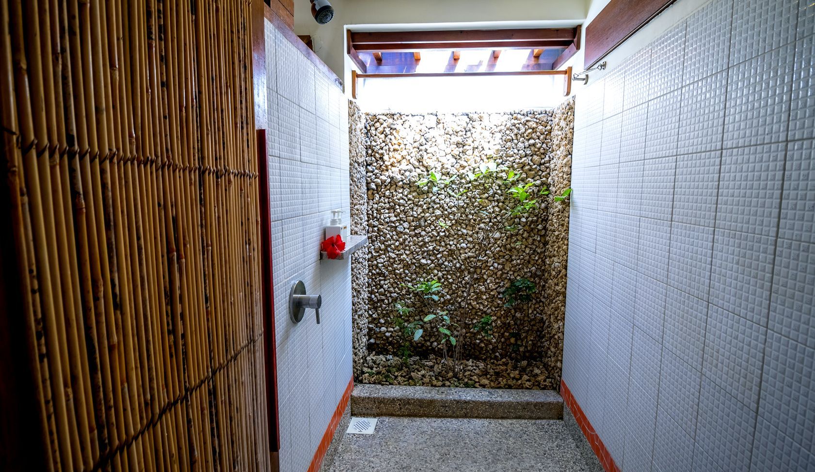 A bathroom with a stone wall and a walk in shower.
