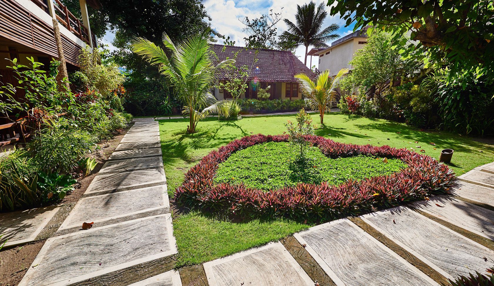 A lush green garden with a stone walkway leading to a house