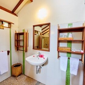 A bathroom with a sink , mirror , shelves and towels.