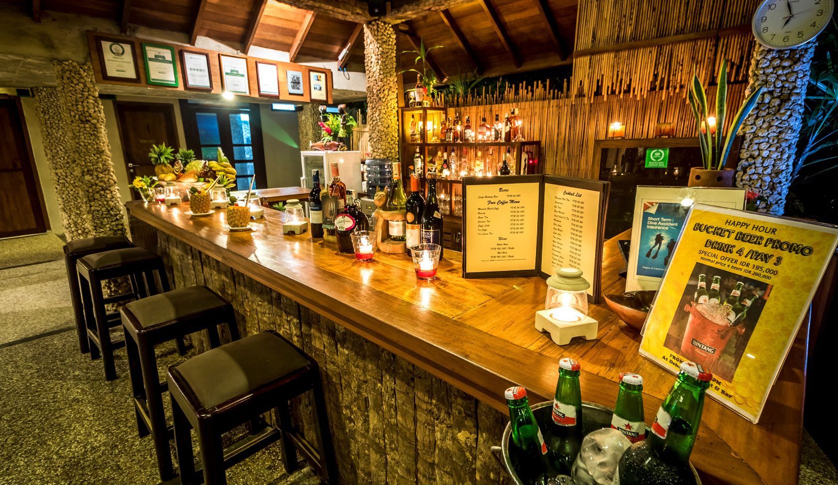 A long wooden bar with stools and bottles of beer on it.