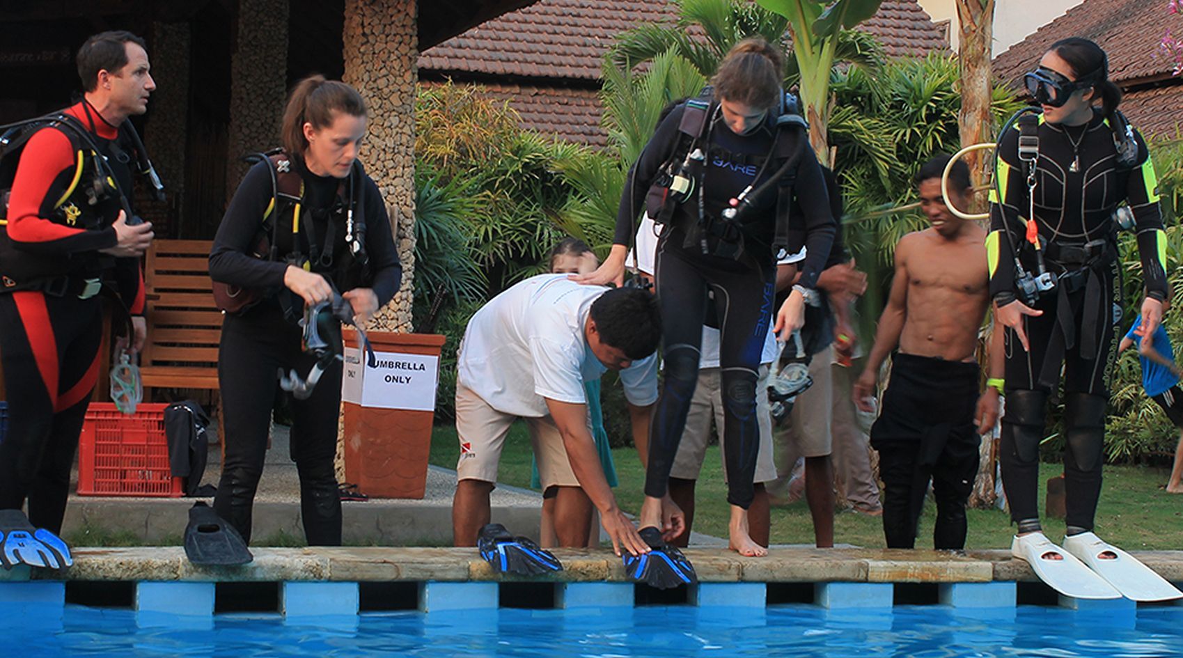 A group of scuba divers are standing next to a pool.