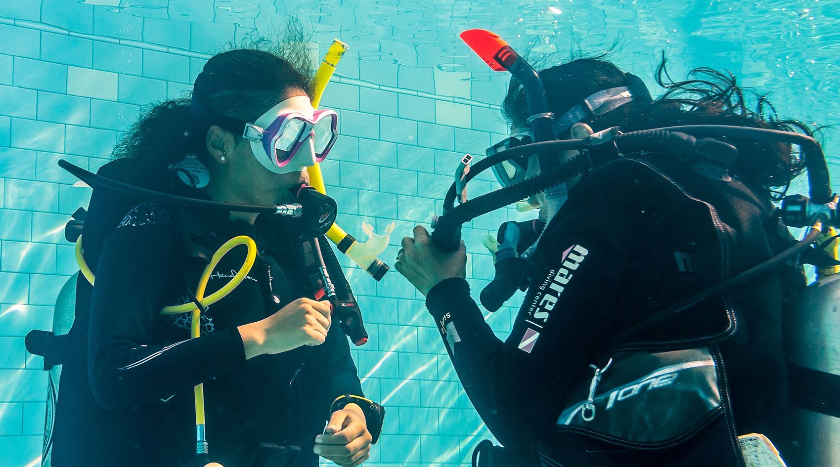 A man and a woman are scuba diving in a pool.