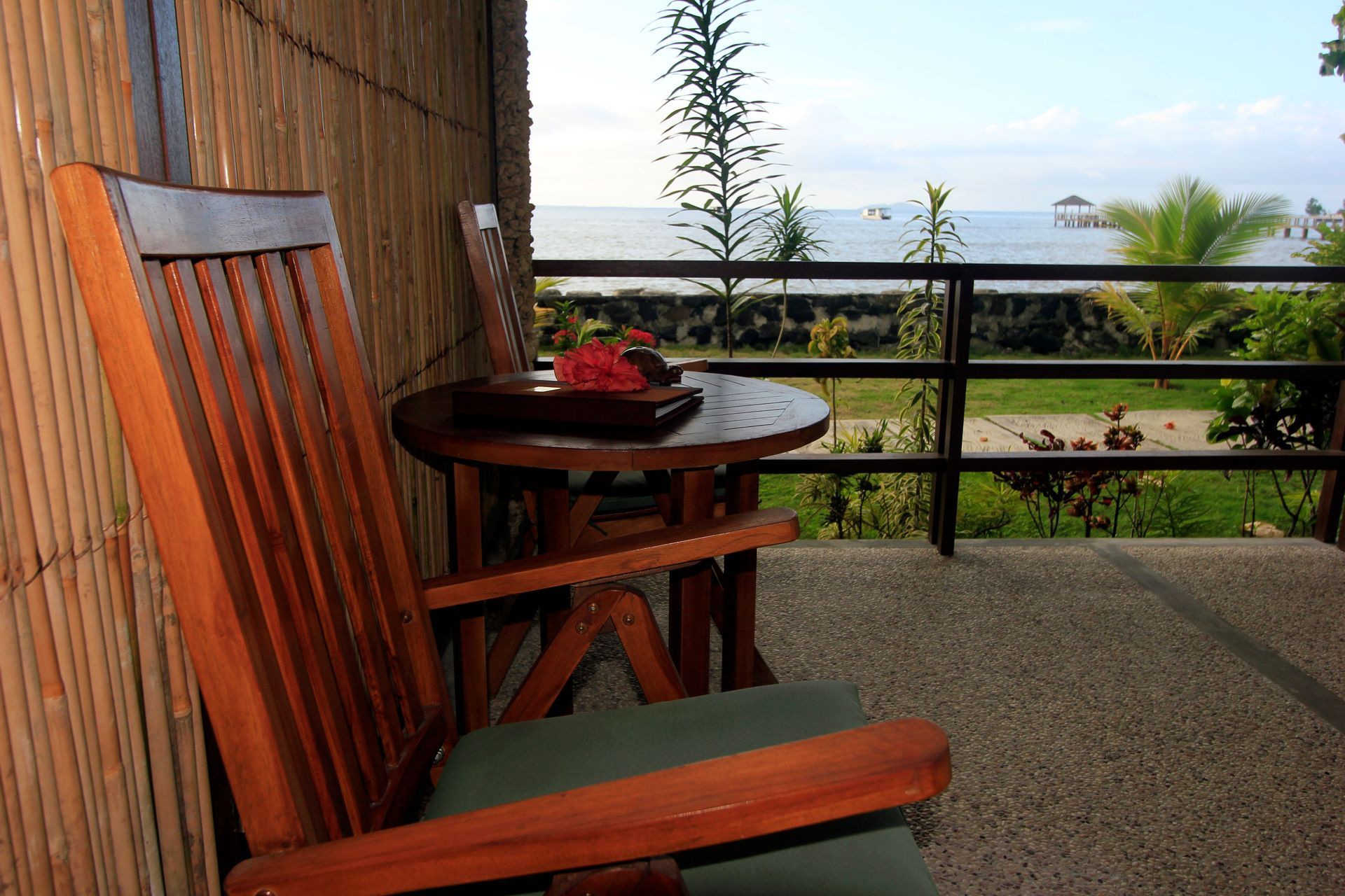 A chair and a table on a balcony overlooking the ocean