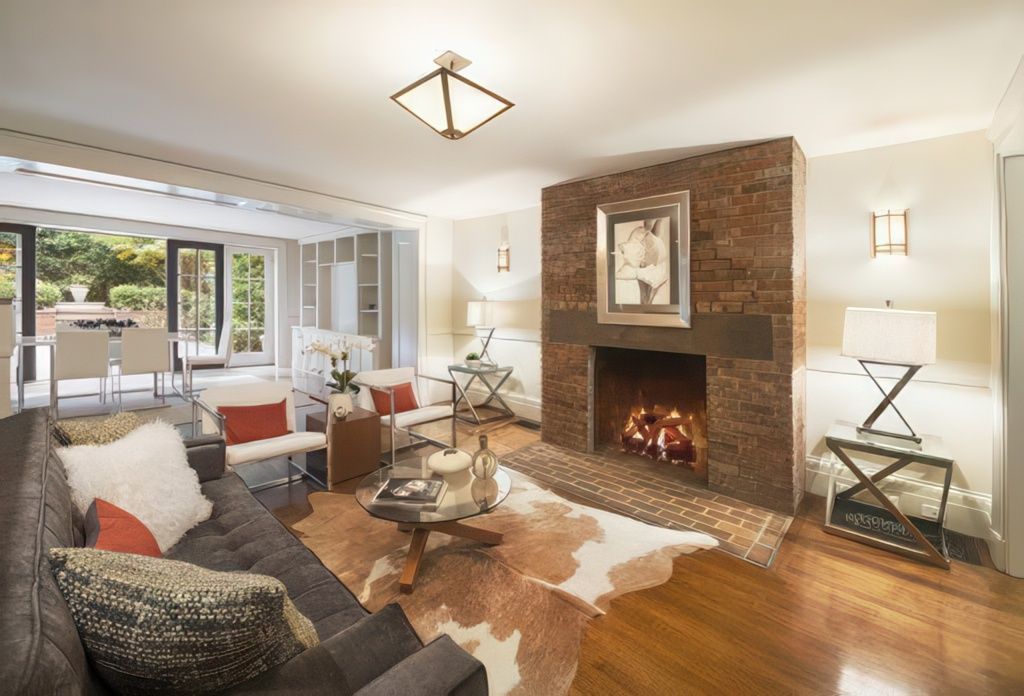 Living room with fireplace, sofa, chairs, rug, and open doors to patio.