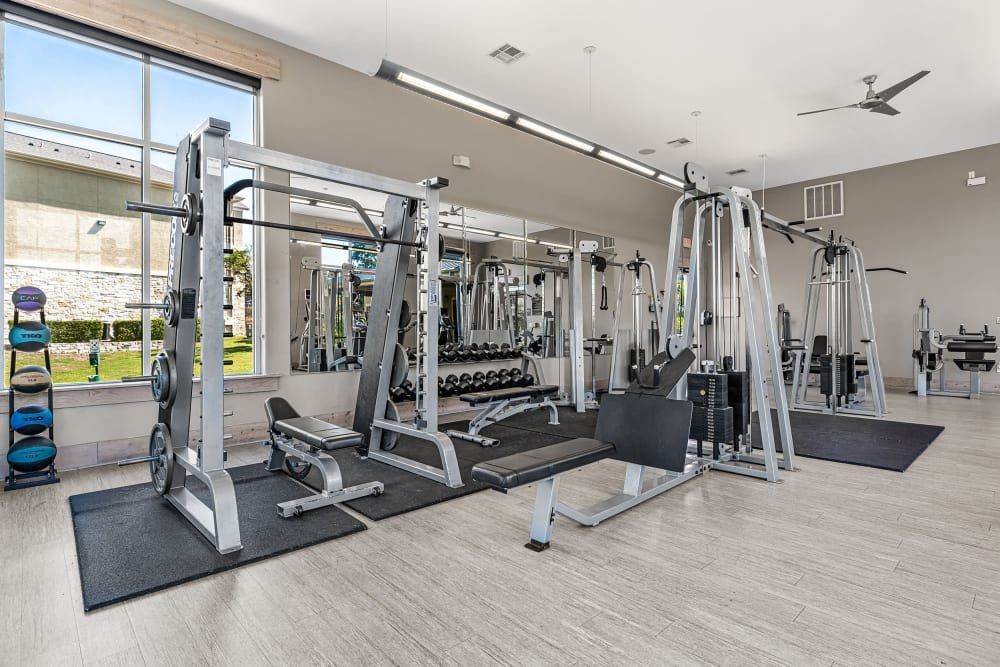 a large gym filled with lots of exercise equipment and a ceiling fan  at Marquis at Canyon Ridge in Austin, TX.