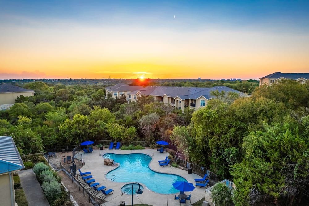 an aerial view of a large swimming pool surrounded by trees at sunset  at Marquis at Canyon Ridge in Austin, TX.