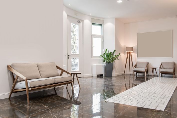 A living room with a couch and chairs and a marble floor.