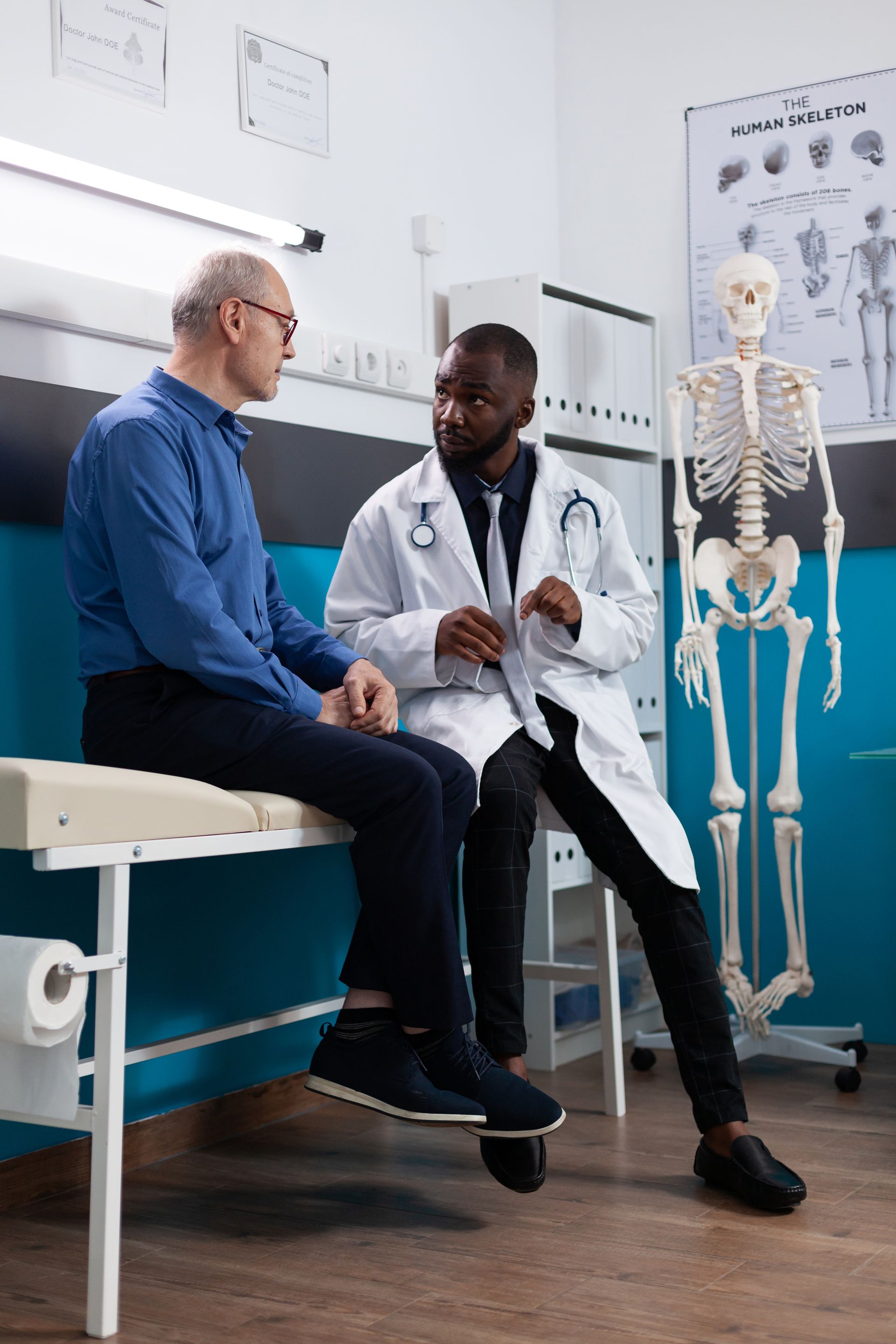 A doctor is talking to a patient who is sitting on a bed.