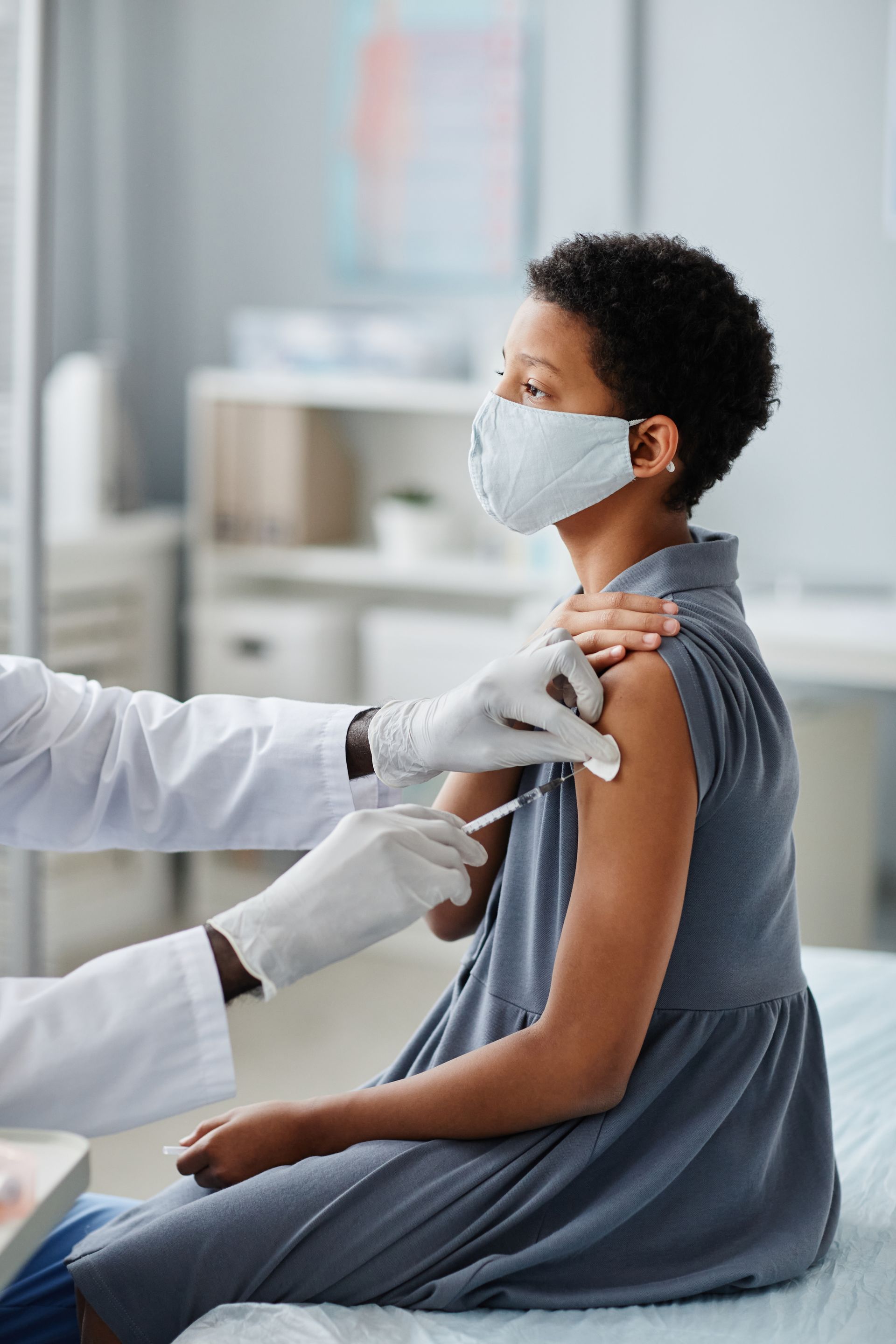 A woman wearing a mask is getting a vaccine from a doctor.