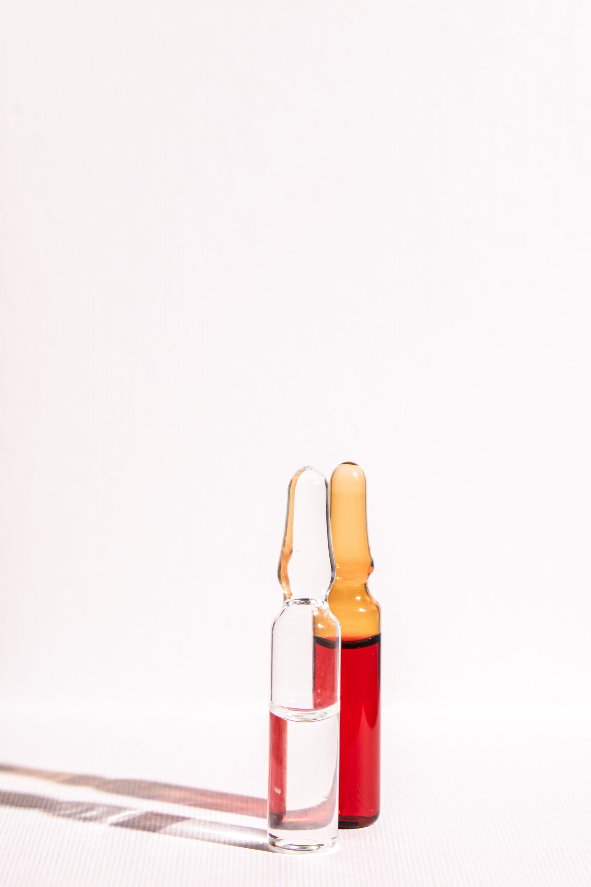 Two bottles of liquid are sitting next to each other on a white surface.