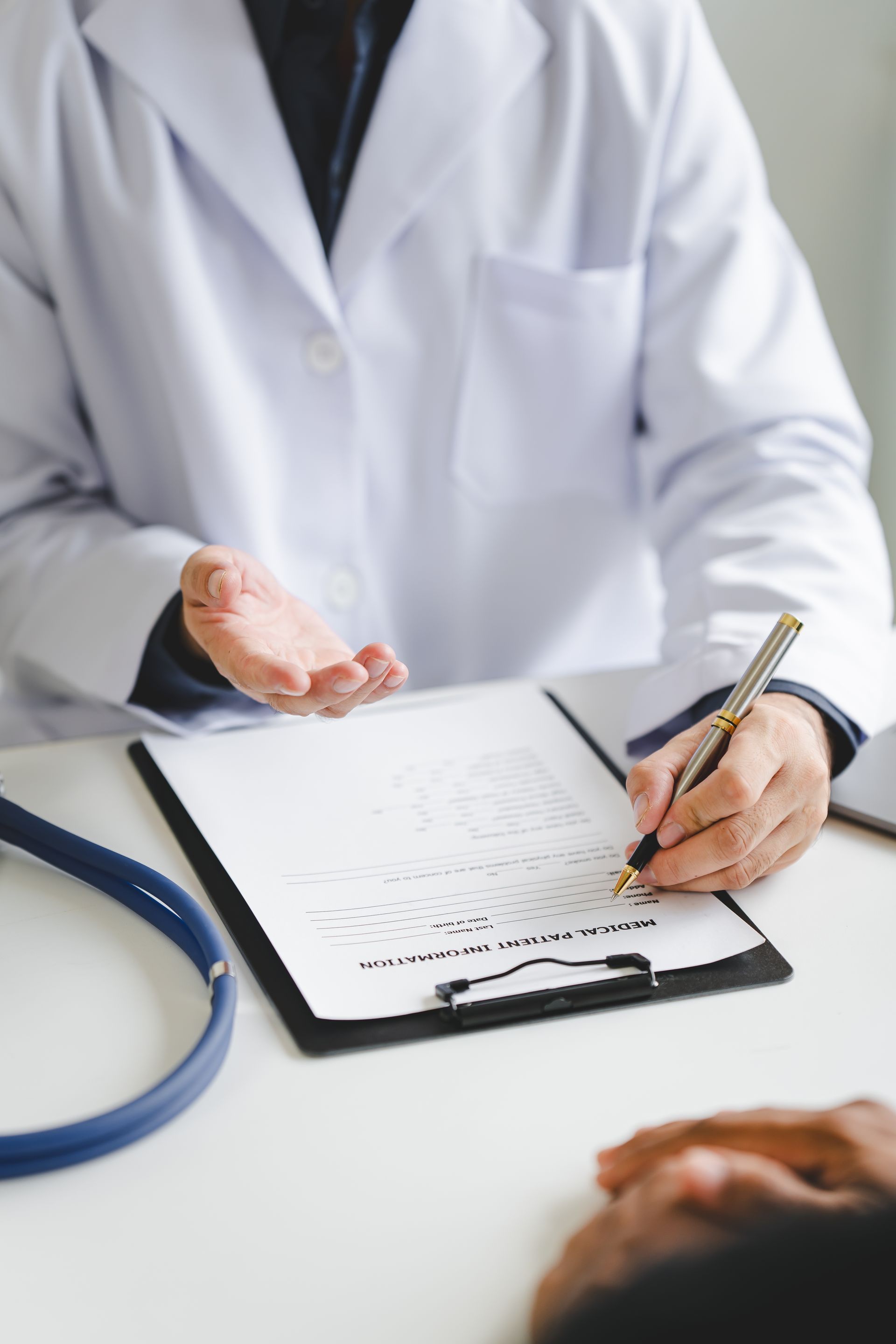 A doctor is writing on a clipboard while talking to a patient.