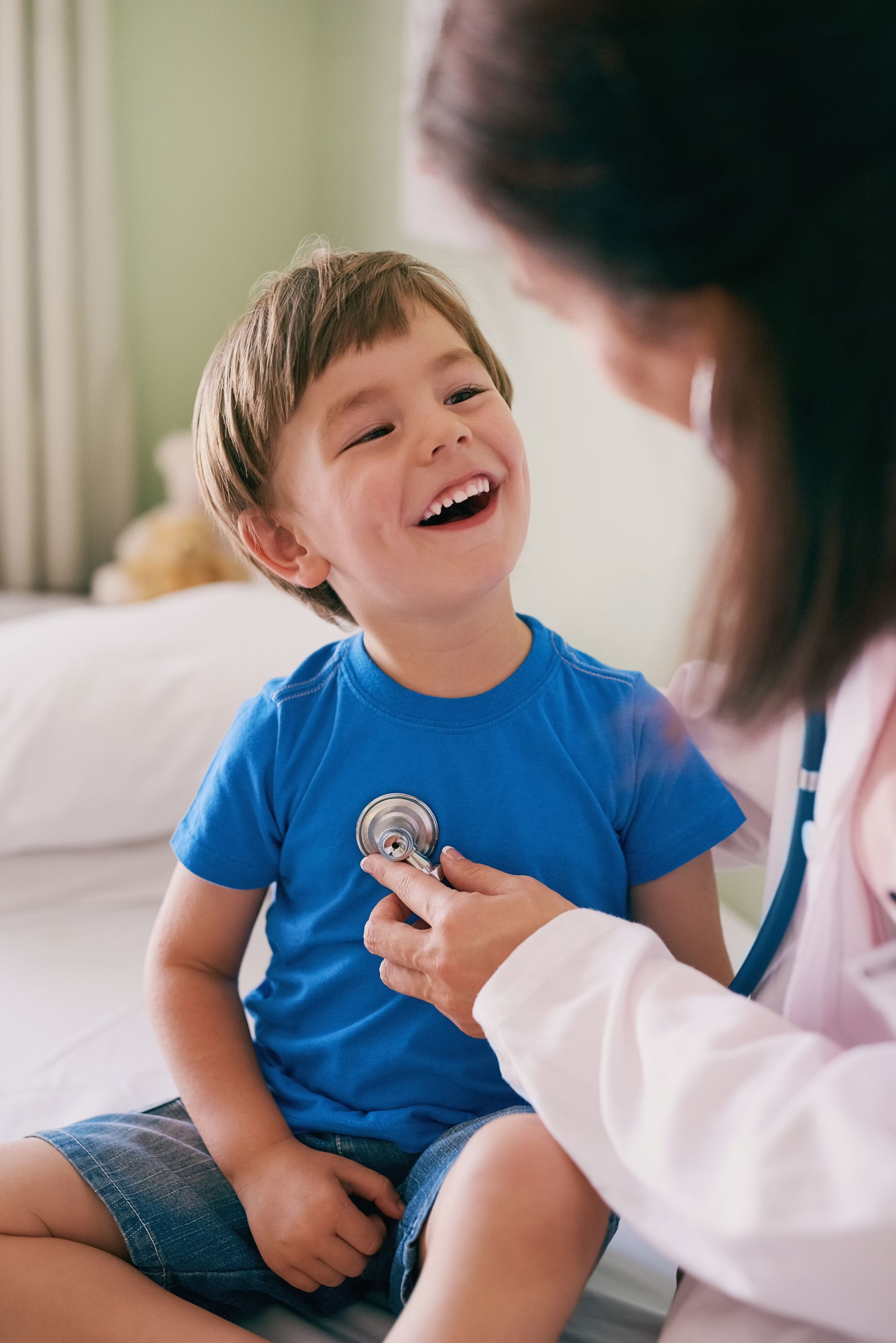 A doctor is listening to a young boy 's heartbeat with a stethoscope.