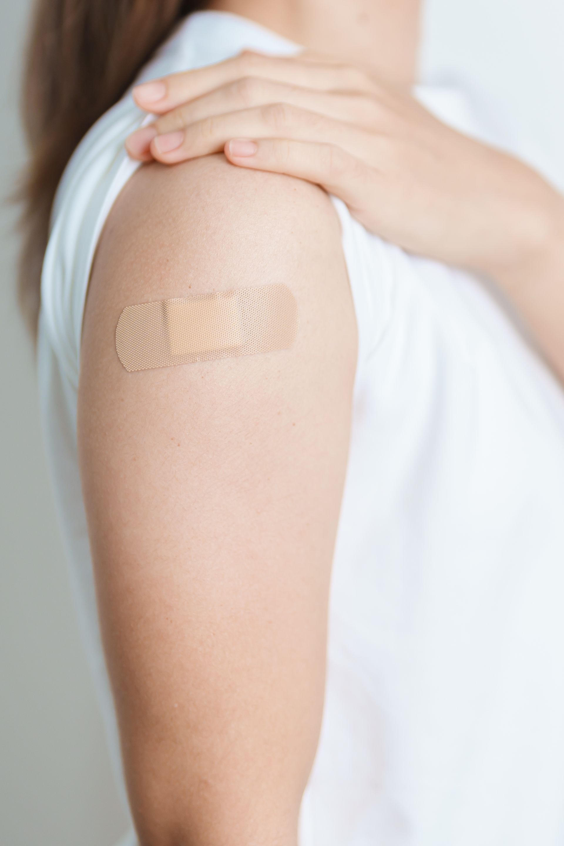 A woman has a bandage on her arm after getting a vaccine.