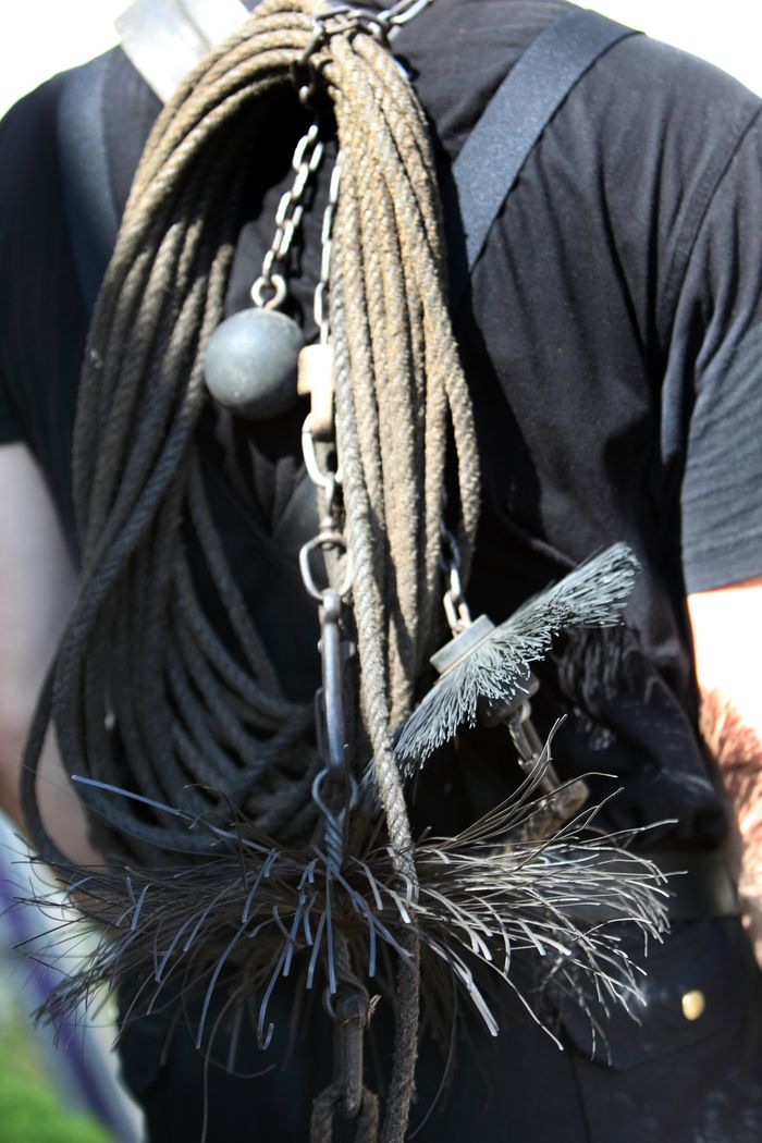 picture of Weighted chain, rope and wire brush for cleaning chimneys being carried on the back of a chimney sweep