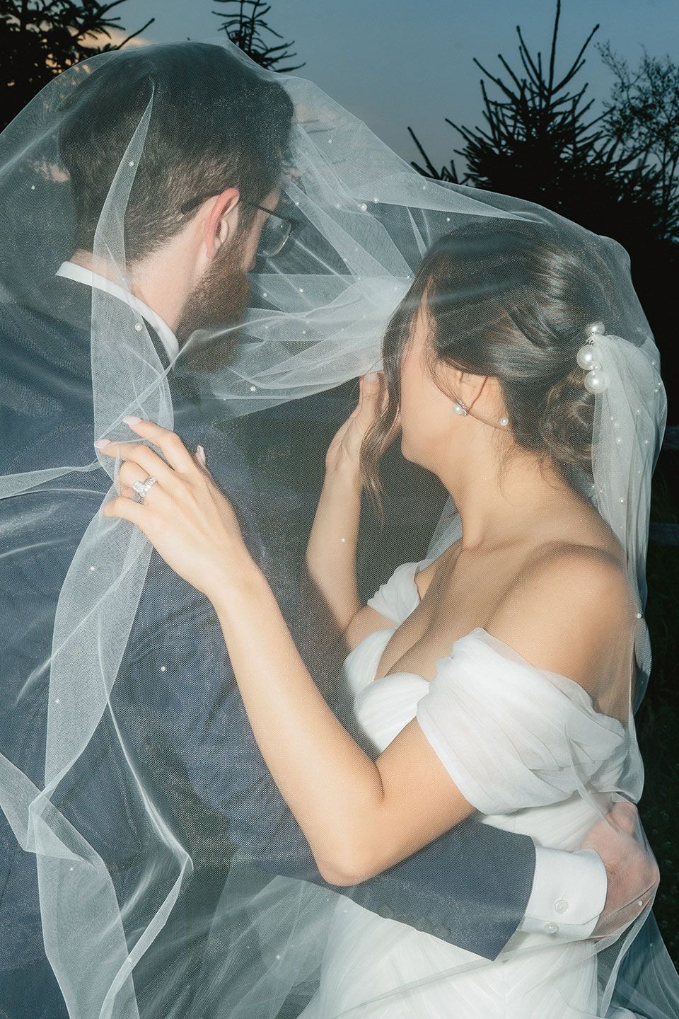 Weddings - Formal black shoes, cologne, watch, rings, and boutonniere on white fabric.