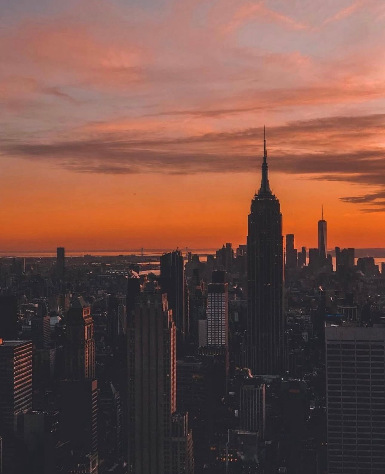 High-Profile Events - City skyline at sunset, orange sky. Empire State Building prominent.