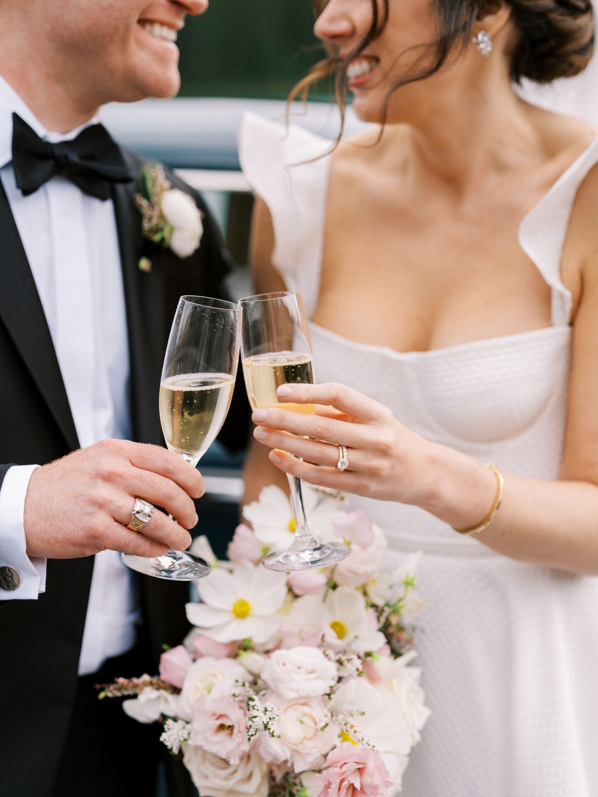 Bride and groom toasting champagne flutes; holding flowers.
